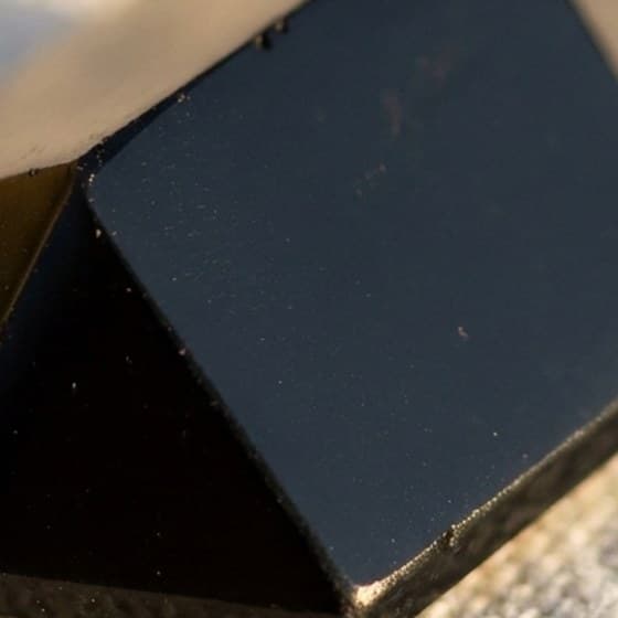 Obsidiana negra facetada sobre linho cru, com o brilho vítreo das faces